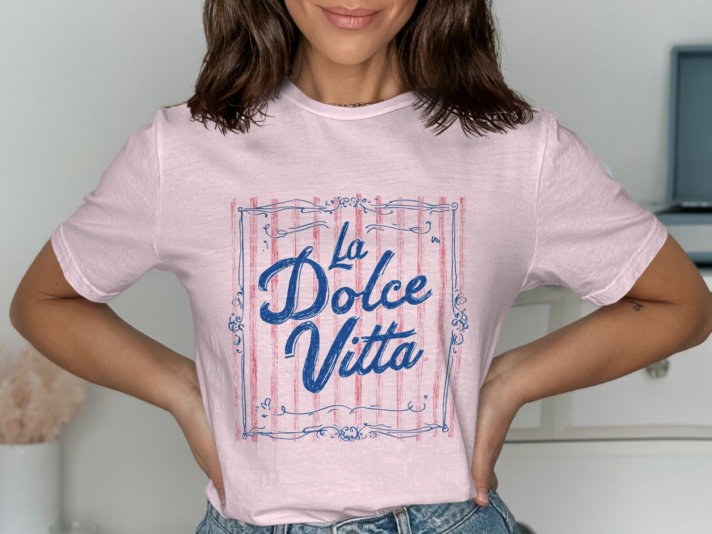 Pink t-shirt with blue "La Dolce Vita" text inside a striped frame.