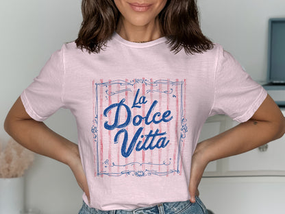 Pink t-shirt with blue "La Dolce Vita" text inside a striped frame.