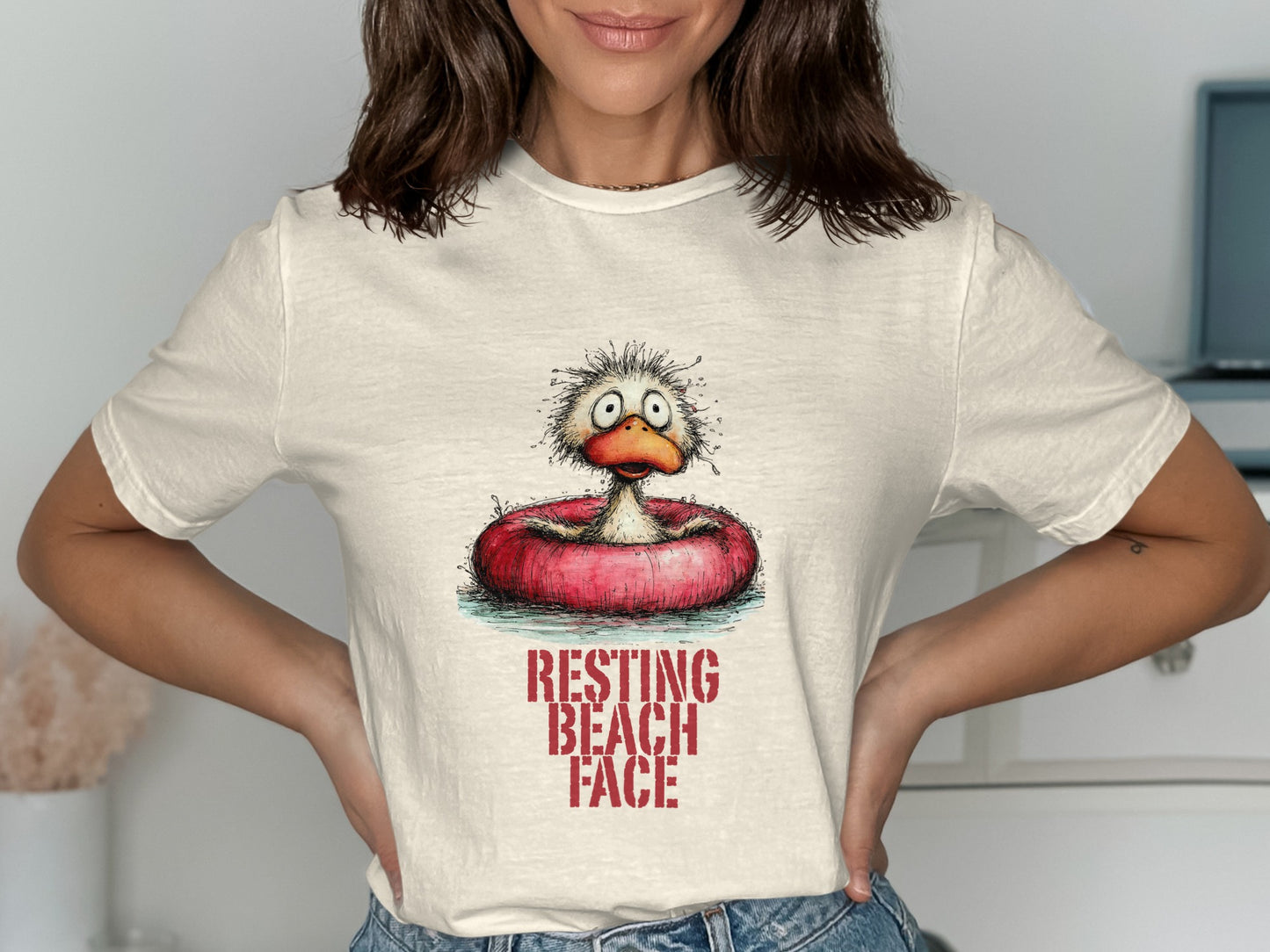 Cream t-shirt with distressed graphic of a cartoon duck in a float, reading "RESTING BEACH FACE".