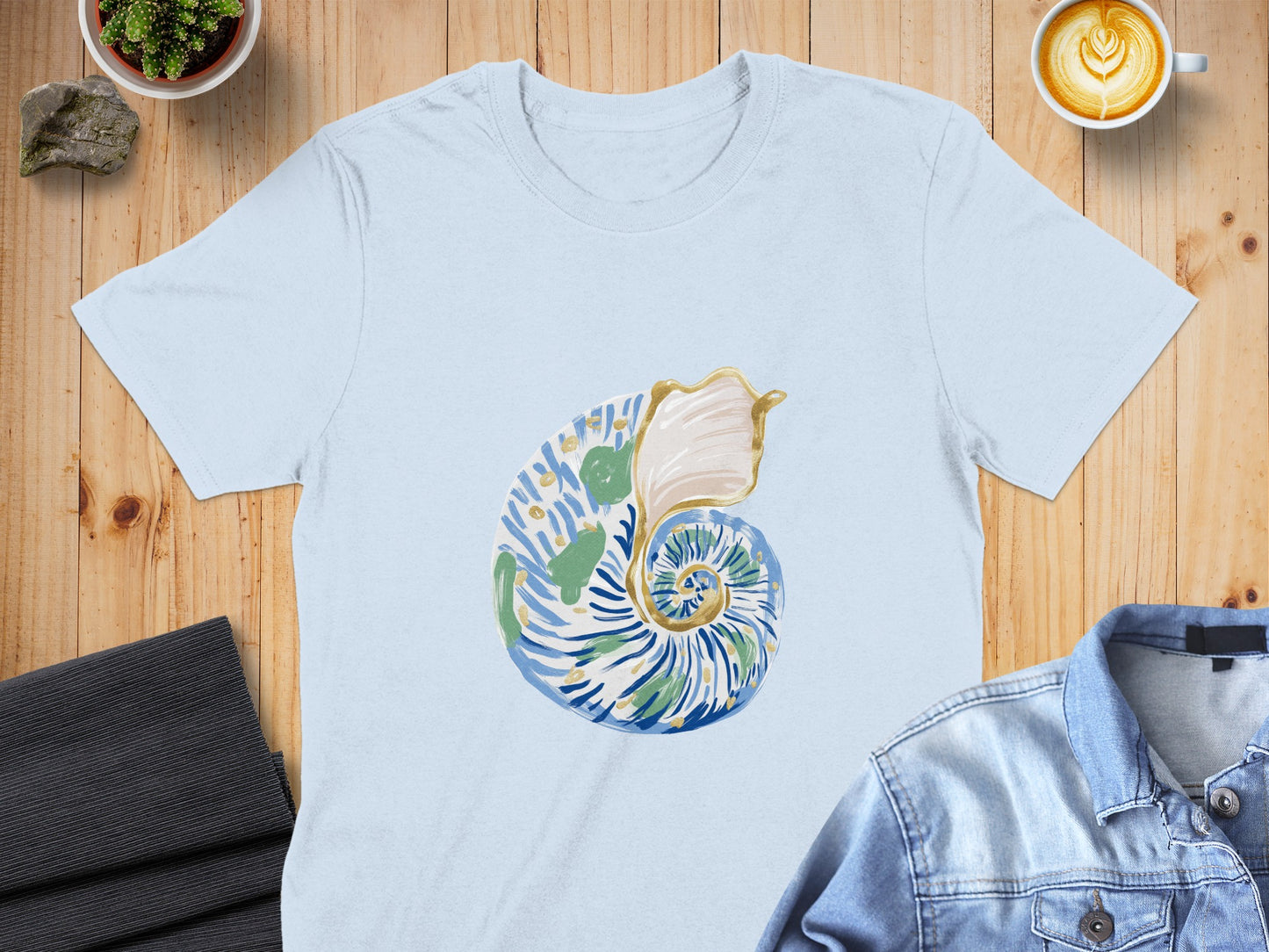 Light blue t-shirt with a blue, green, and gold seashell graphic.