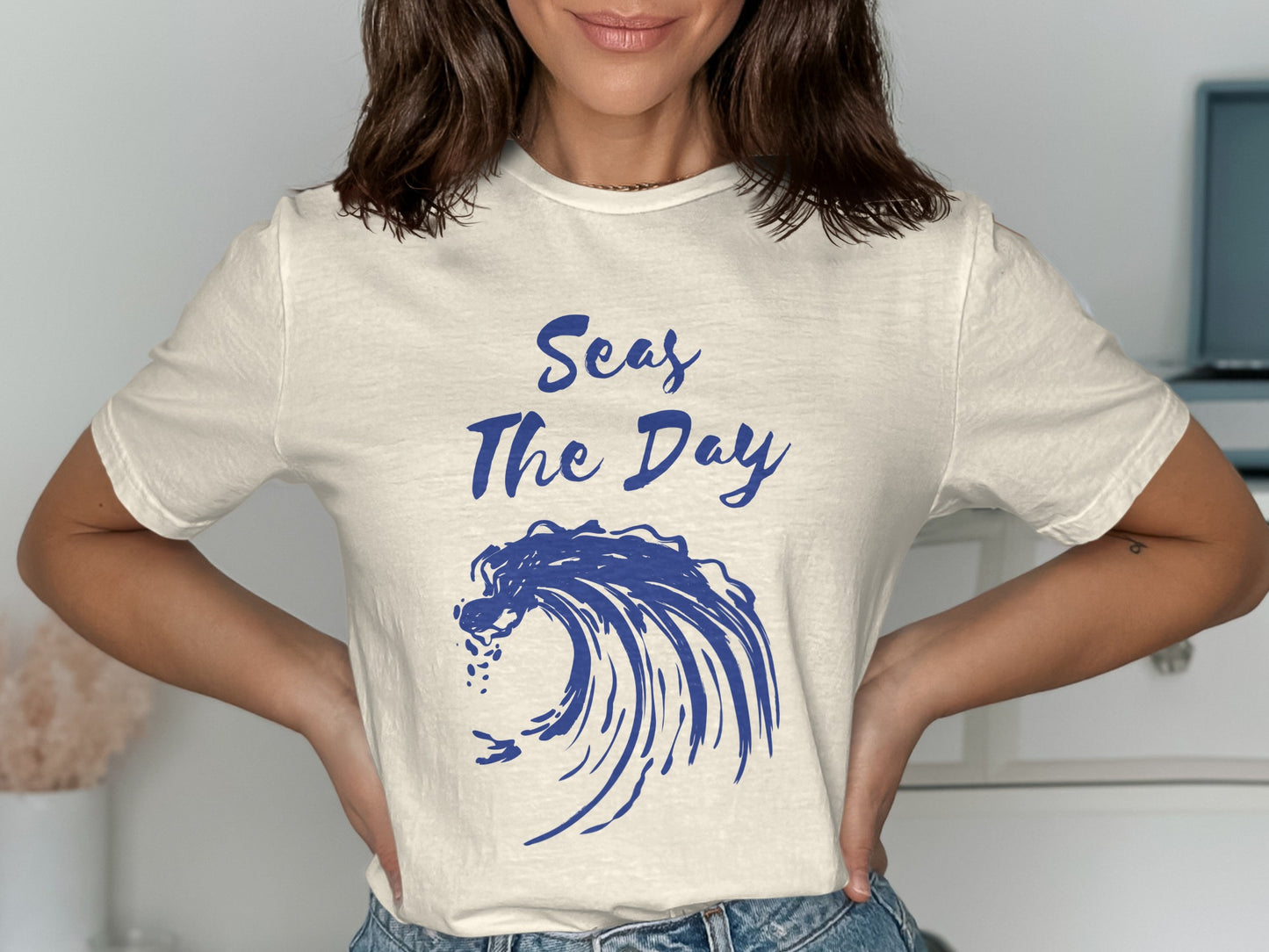 Cream t-shirt with blue wave graphic and "Seas The Day" text.