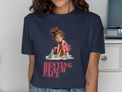 Woman in navy t-shirt with illustration of girl building sandcastle, text RESTING BEACH FACE.