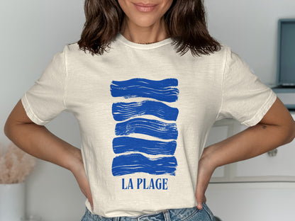 Cream t-shirt with blue brushstroke waves and text "LA PLAGE".