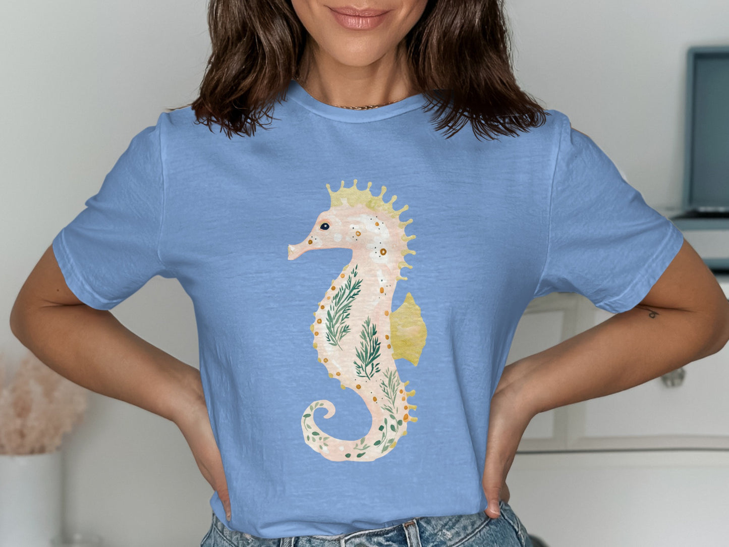 Light blue t-shirt featuring a watercolor seahorse with green fern accents.