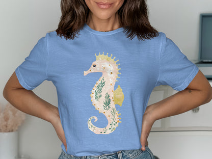 Light blue t-shirt featuring a watercolor seahorse with green fern accents.