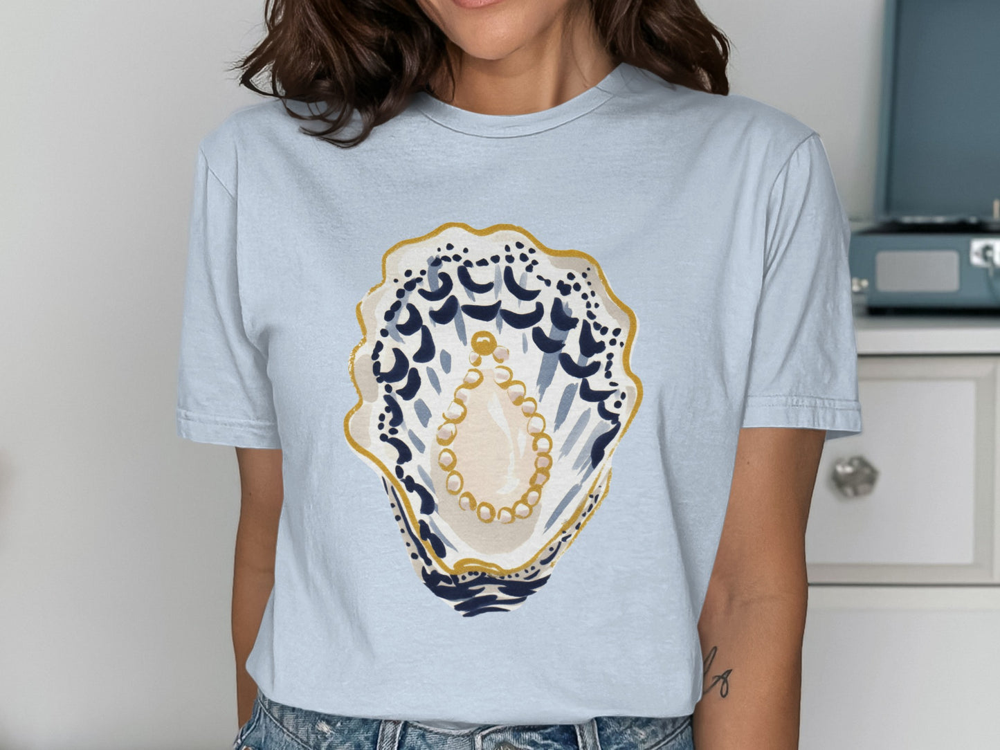 Light blue t-shirt with a painted oyster shell and pearl design.