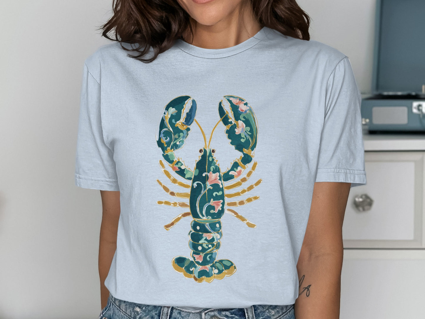 Light blue t-shirt with a stylized, ornate lobster graphic.