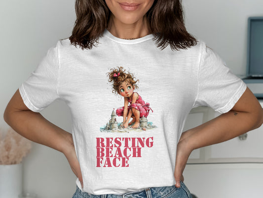 White t-shirt with illustration of a girl building sandcastles with text "RESTING BEACH FACE".