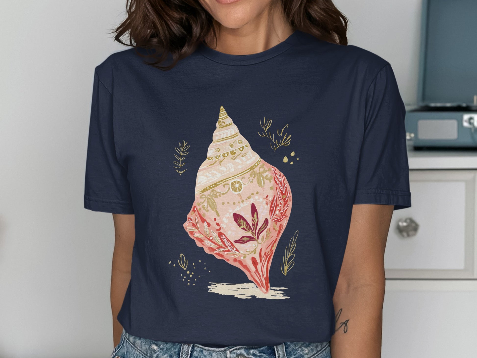 Navy t-shirt with a detailed illustration of a pink and gold seashell.