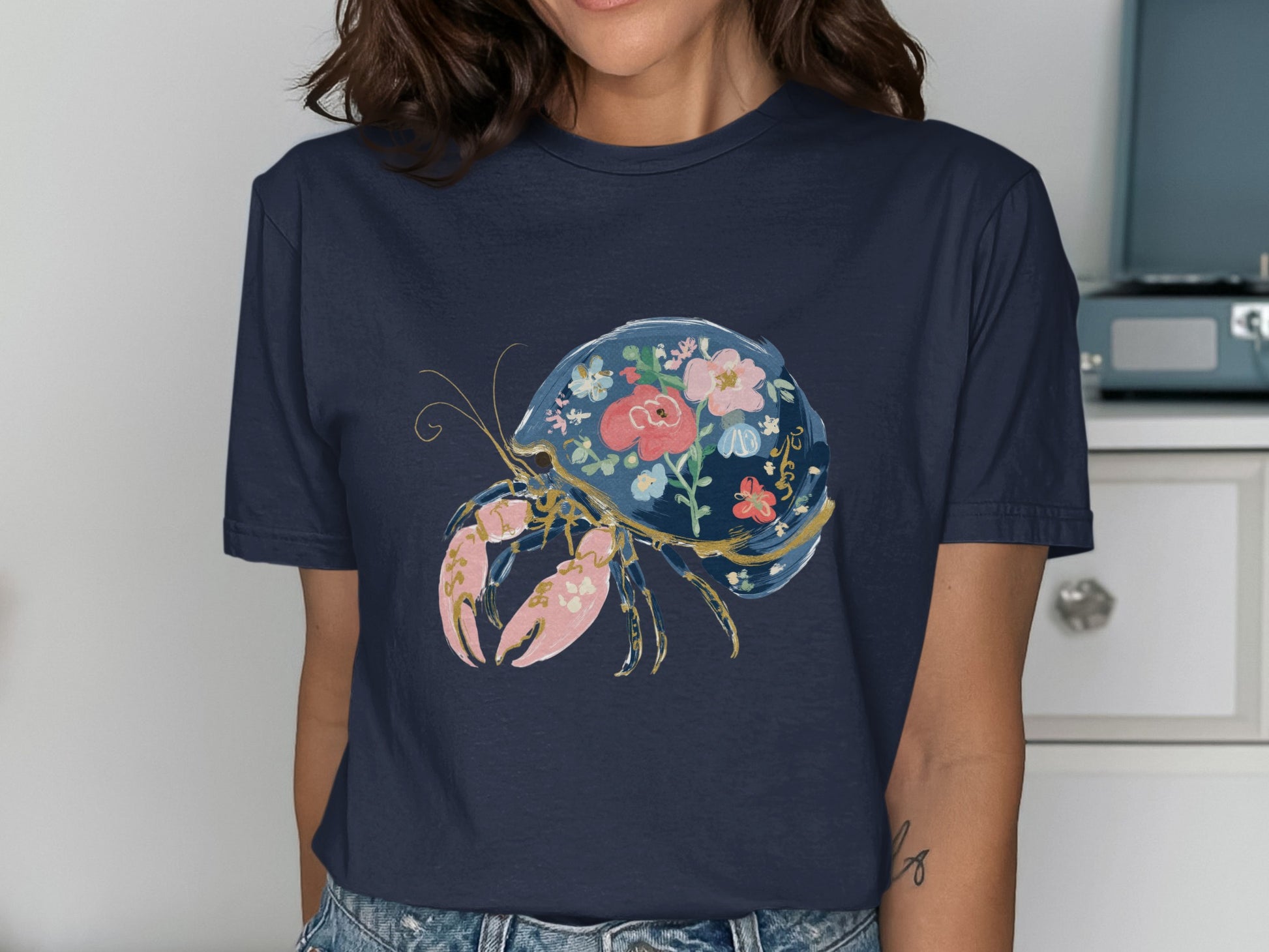 Dark navy t-shirt with a painted crab illustration featuring floral and gold accents.