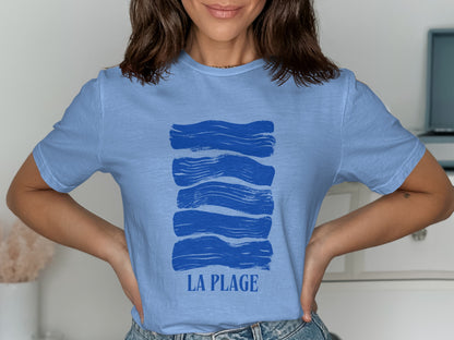 Blue t-shirt with five horizontal blue brushstrokes and the text "LA PLAGE" below.
