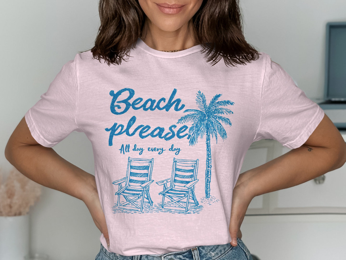 Light pink t-shirt with blue palm tree, beach chairs, and text.
