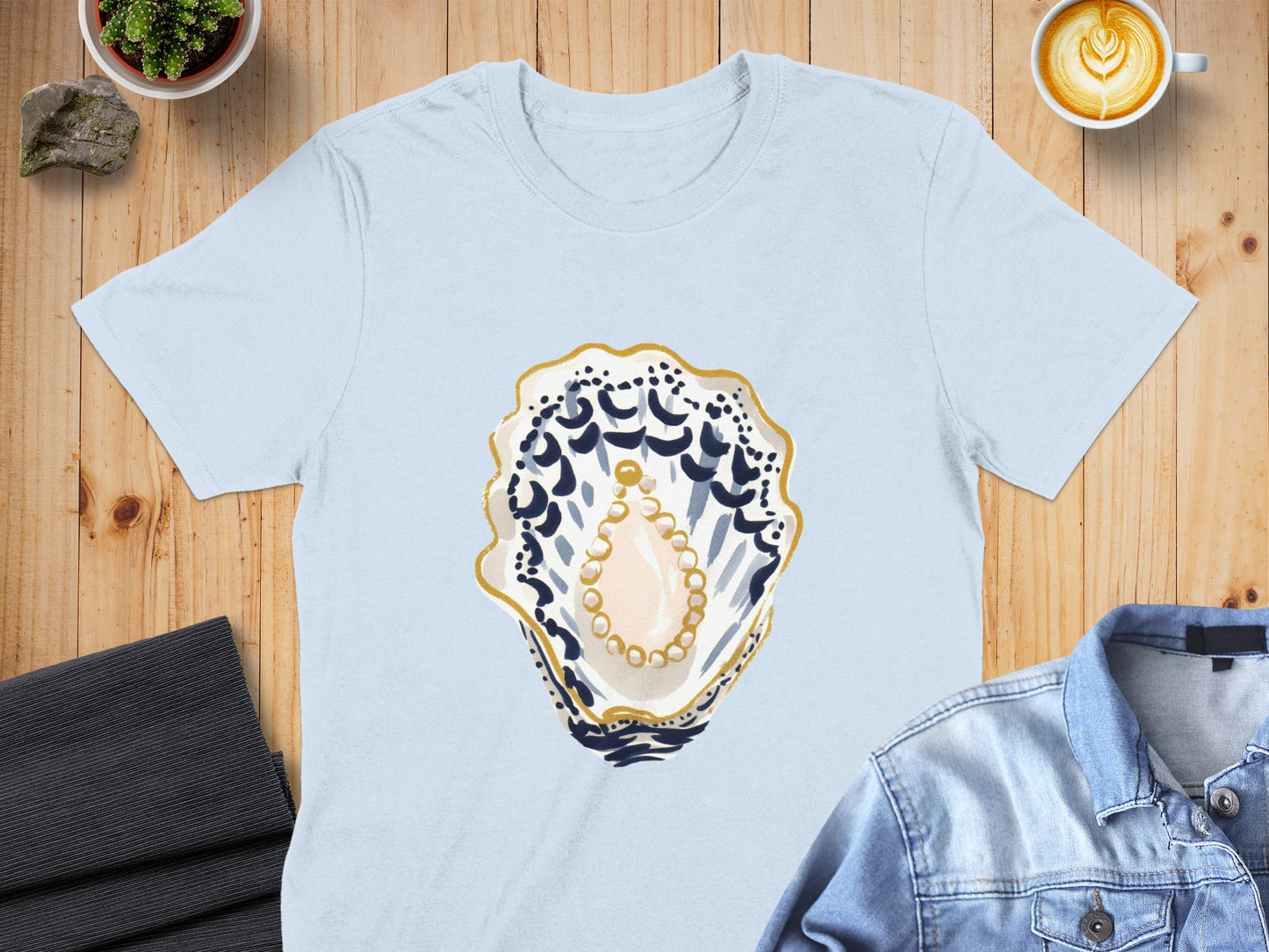 Light blue t-shirt with a pearl and oyster shell graphic.