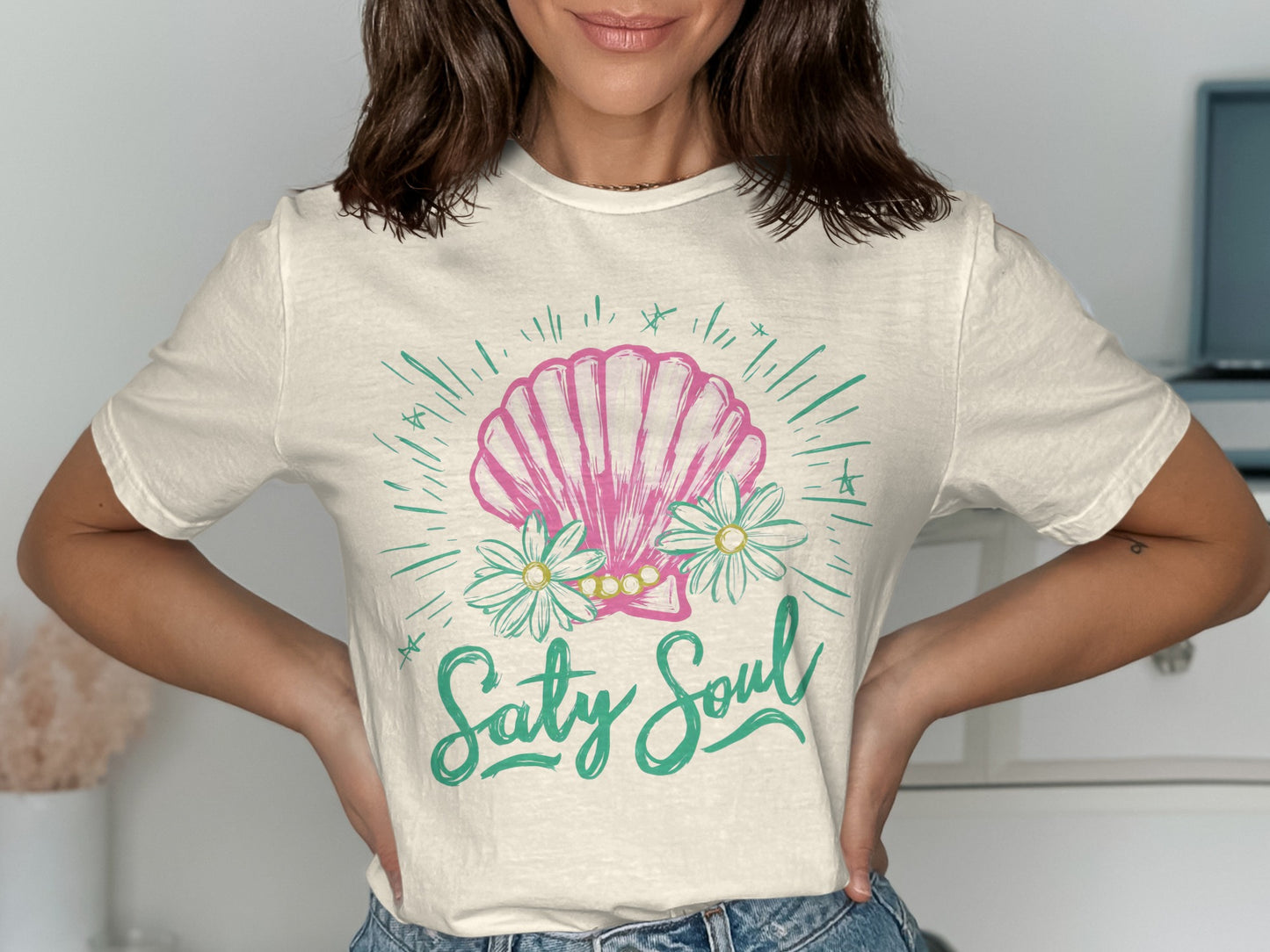 Cream t-shirt with a pink seashell, daisies, and "Salty Soul" text.