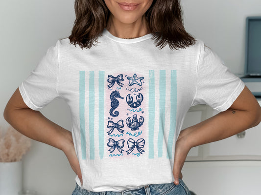 White t-shirt with blue and pink stripes featuring nautical icons: bows, seahorse, lobster, and starfish.