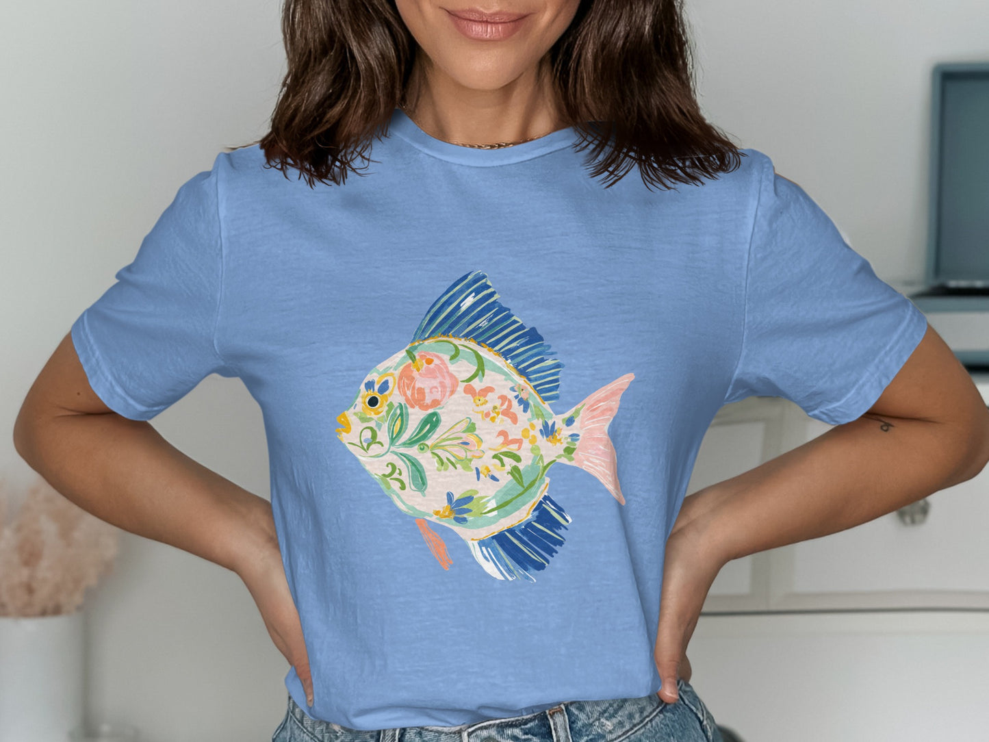 Blue t-shirt with a stylized fish illustration featuring floral patterns.