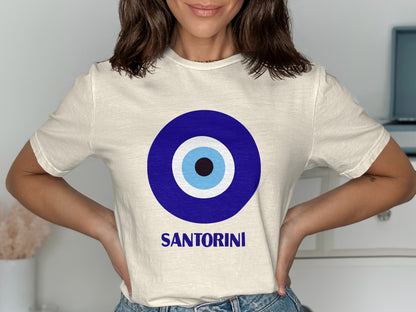 Cream t-shirt with a blue and white evil eye graphic and "Santorini" text.