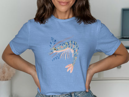 Light blue t-shirt with a watercolor-style shrimp illustration in pinks and blues.
