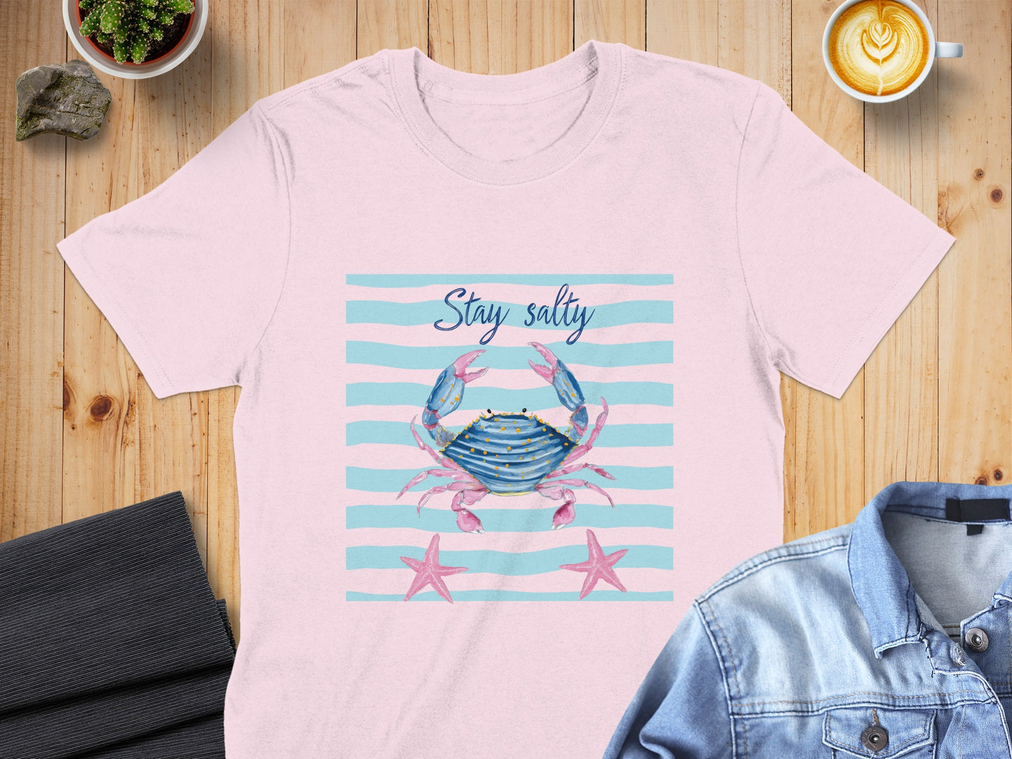 Pink t-shirt with blue crab, starfish, and "Stay Salty" text on striped background.