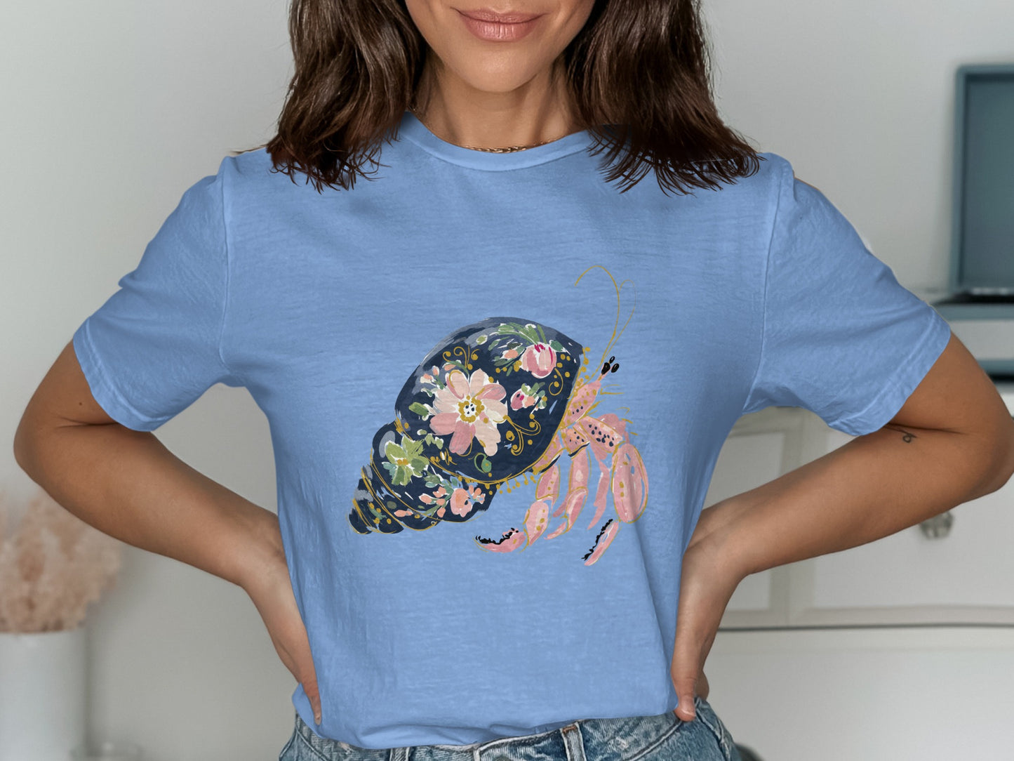 Blue t-shirt with a decorative hermit crab and floral shell graphic.