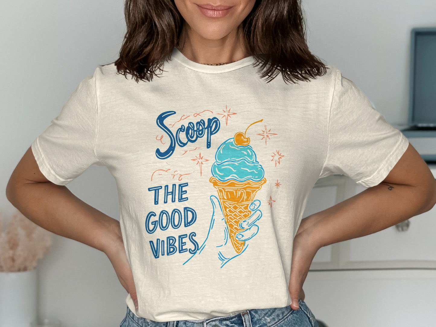 Cream t-shirt with blue text "Scoop the good vibes" and ice cream cone illustration.
