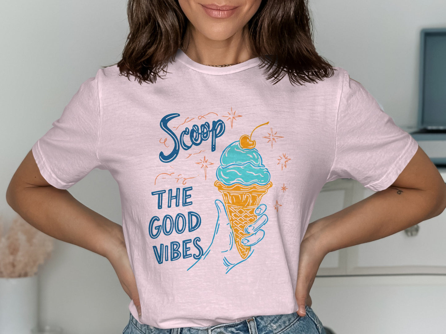 Pink t-shirt with blue text "Scoop the good vibes" and an ice cream cone illustration.