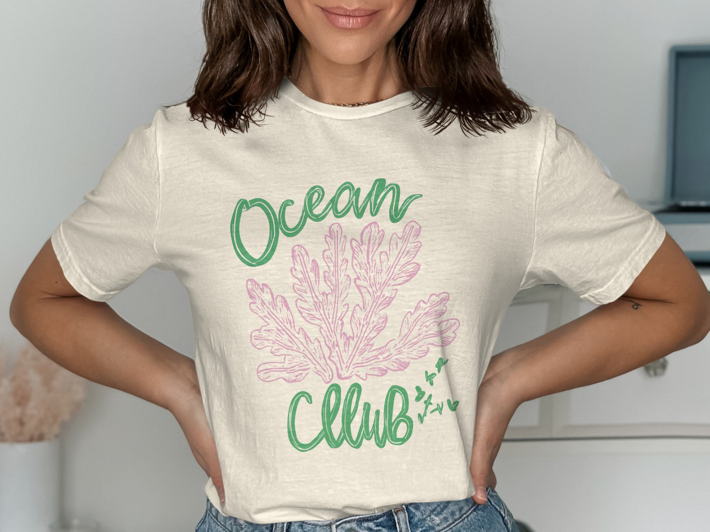 Cream t-shirt with green "Ocean" and pink "Club" text and coral graphic.