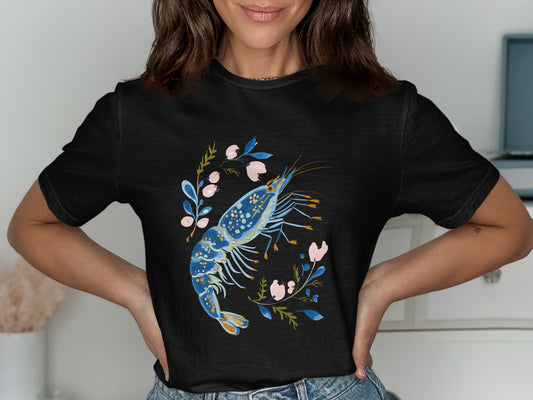 Black t-shirt with a watercolor illustration of a blue shrimp and pink flowers.