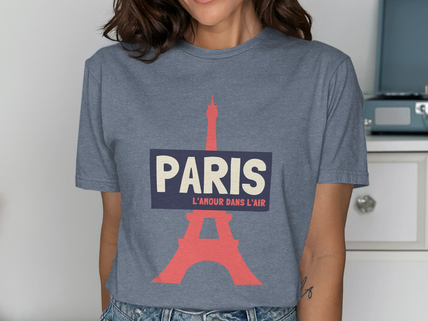 Grey t-shirt with Paris Eiffel Tower graphic and text "PARIS L'AMOUR DANS L'AIR".