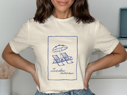 T-shirt with sketch of two lounge chairs under an umbrella and text "Live slow, more sun".