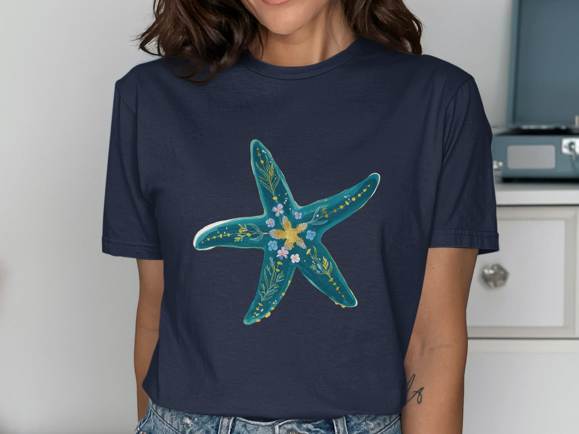 Navy t-shirt with a teal starfish design and floral accents.