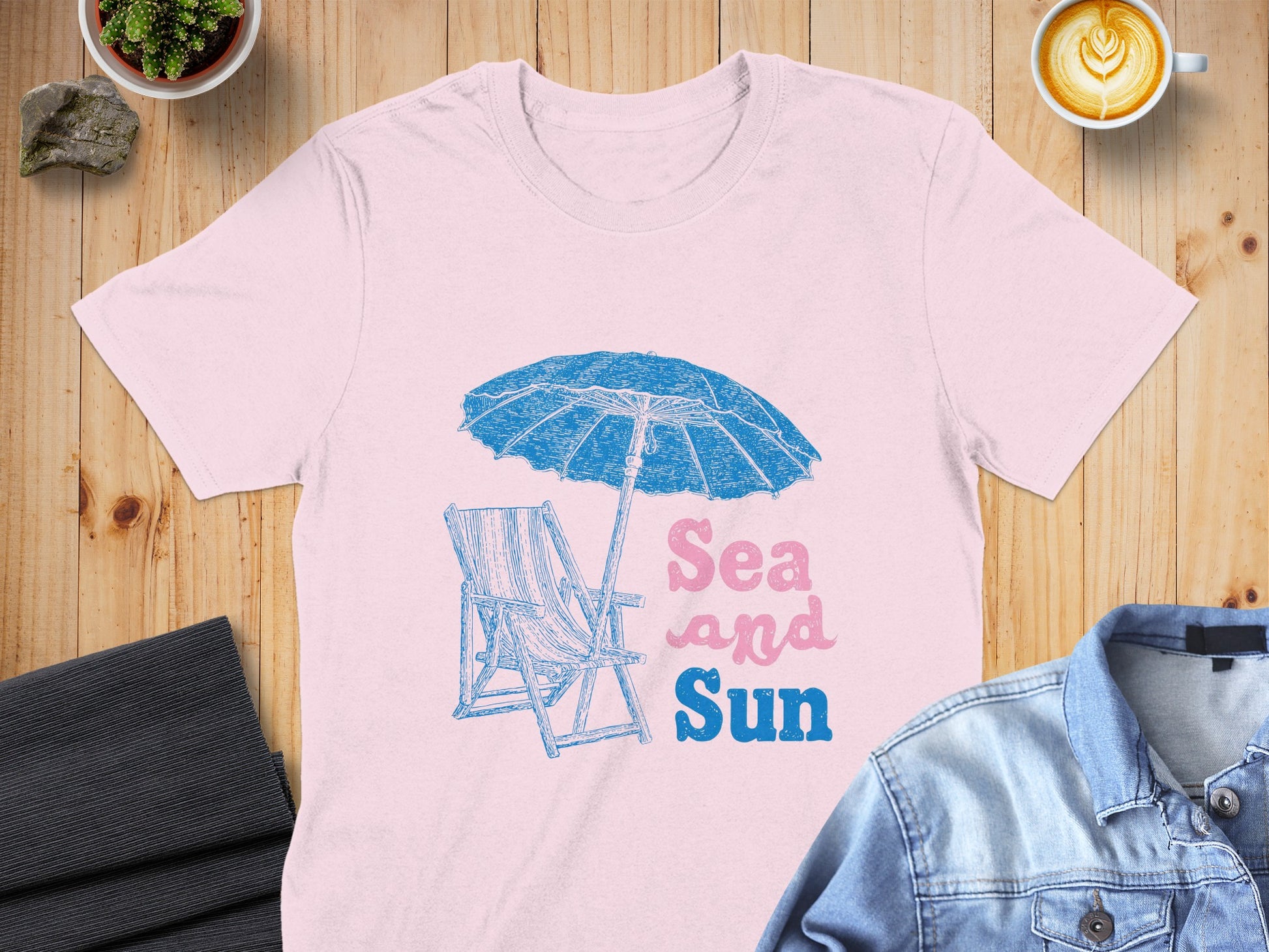 Pink t-shirt with beach chair, umbrella, and "Sea and Sun" text.