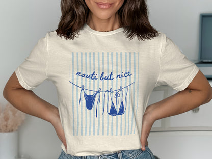 Cream t-shirt with "nauti but nice" text and bikini hanging on clothesline.