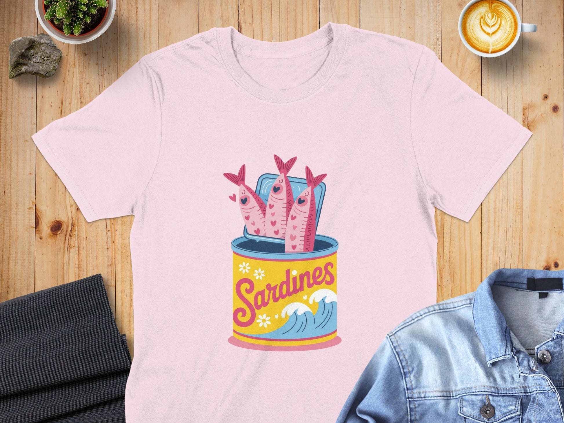 Pink t-shirt featuring a can of sardines with smiling fish.