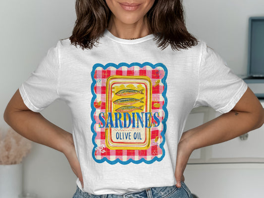 White t-shirt with a vintage sardine can label design featuring blue, yellow, and red plaid border.
