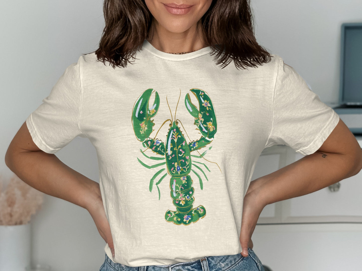 Cream t-shirt with a green lobster design featuring blue floral accents.