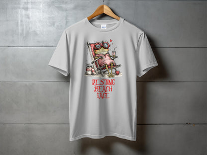 Grey t-shirt with a cartoon frog in sunglasses relaxing in a beach chair.