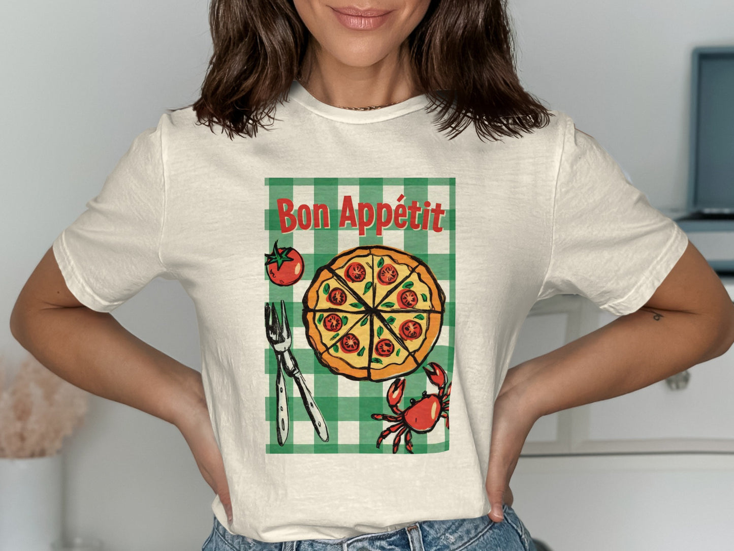 White t-shirt with Bon Appétit pizza graphic, checkered background, fork, and crab.