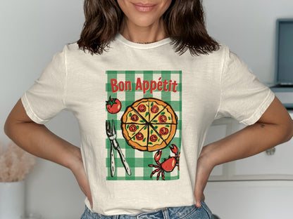 White t-shirt with Bon Appétit pizza graphic, checkered background, fork, and crab.