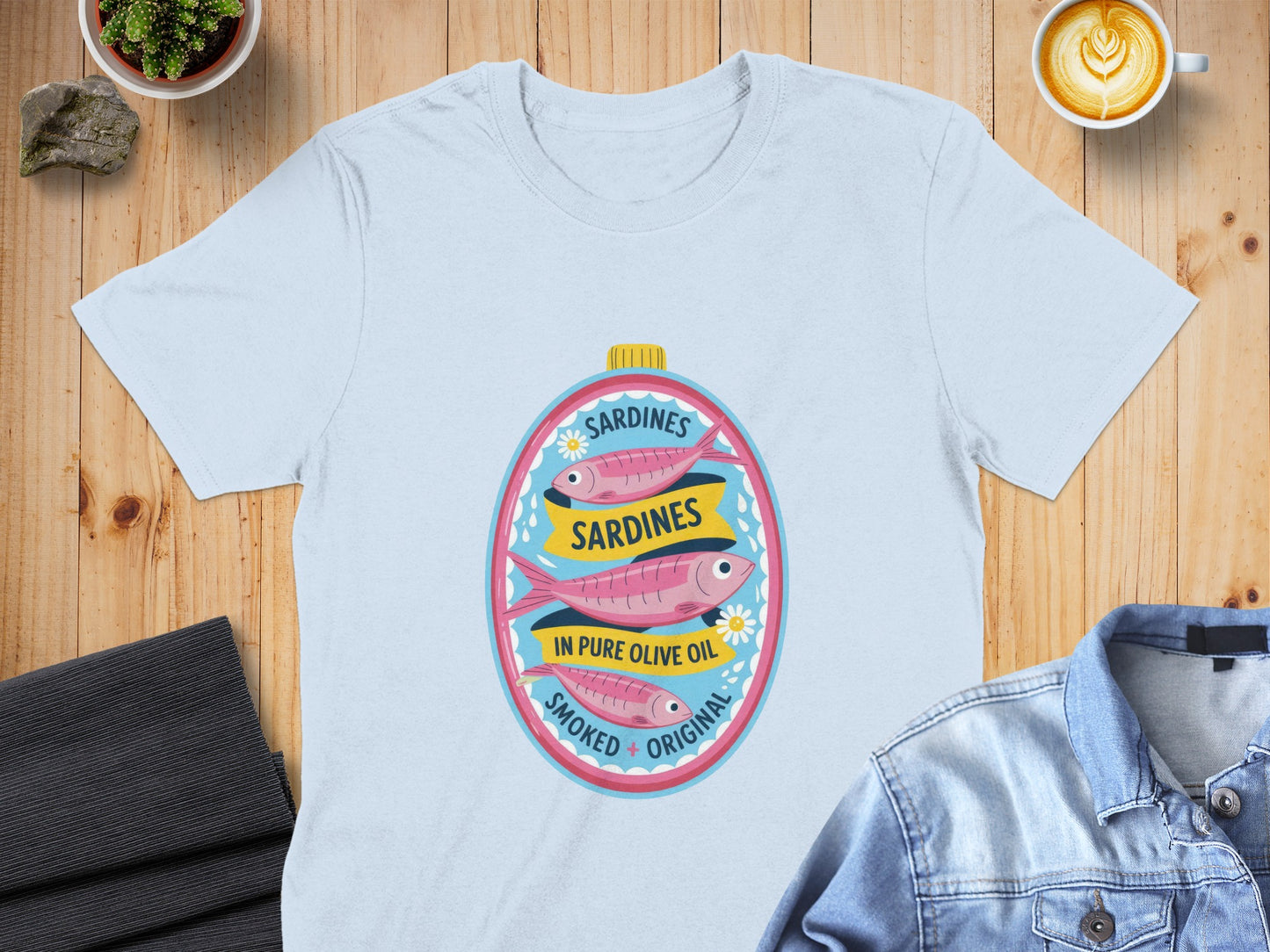 Light blue t-shirt featuring oval graphic of three pink sardines in oil.