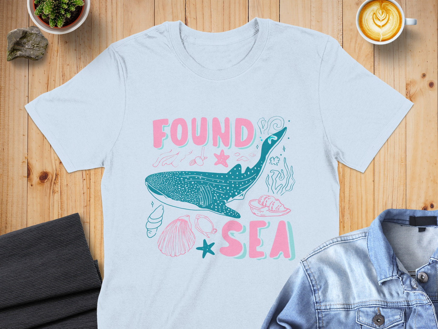 Light blue t-shirt with whale shark and ocean graphic, "FOUND AT SEA" text.