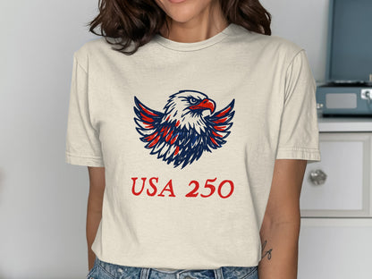 Cream t-shirt with a patriotic eagle graphic and "USA 250" text.