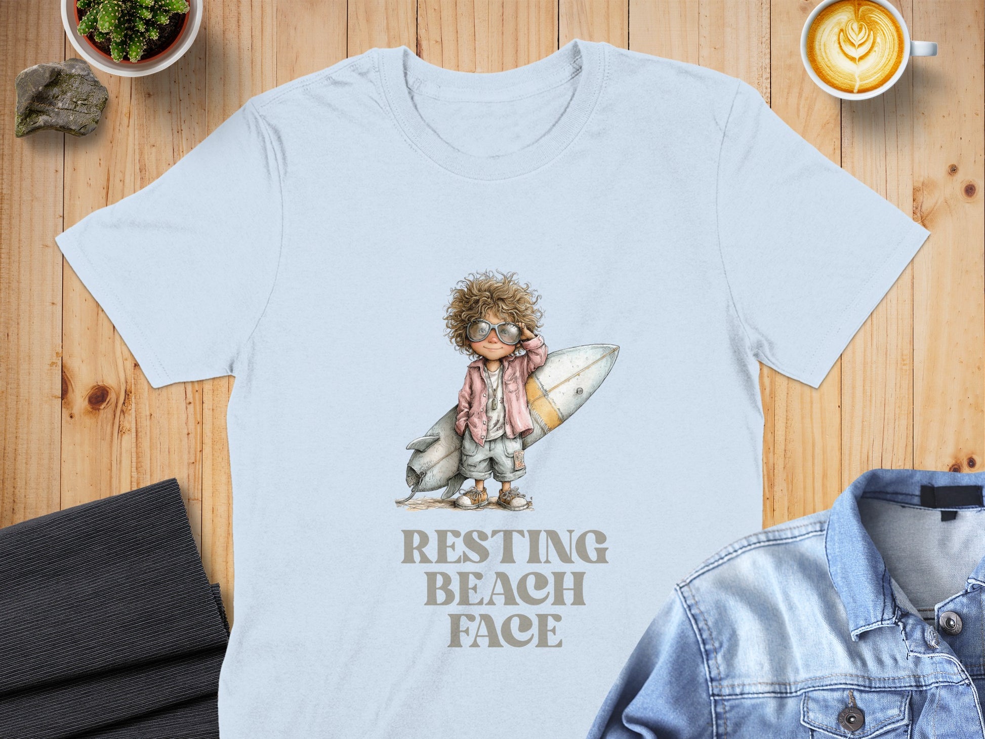 Light blue t-shirt with a graphic of a child with sunglasses holding a surfboard.