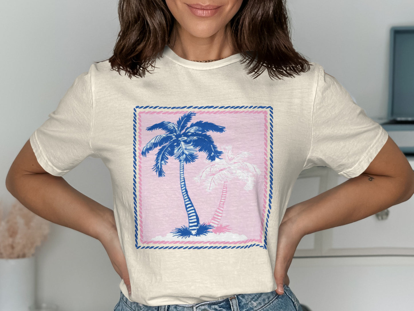 Cream t-shirt with a pink and blue graphic of two palm trees.