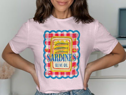 Pink t-shirt featuring a graphic of sardines in olive oil within a gingham border.