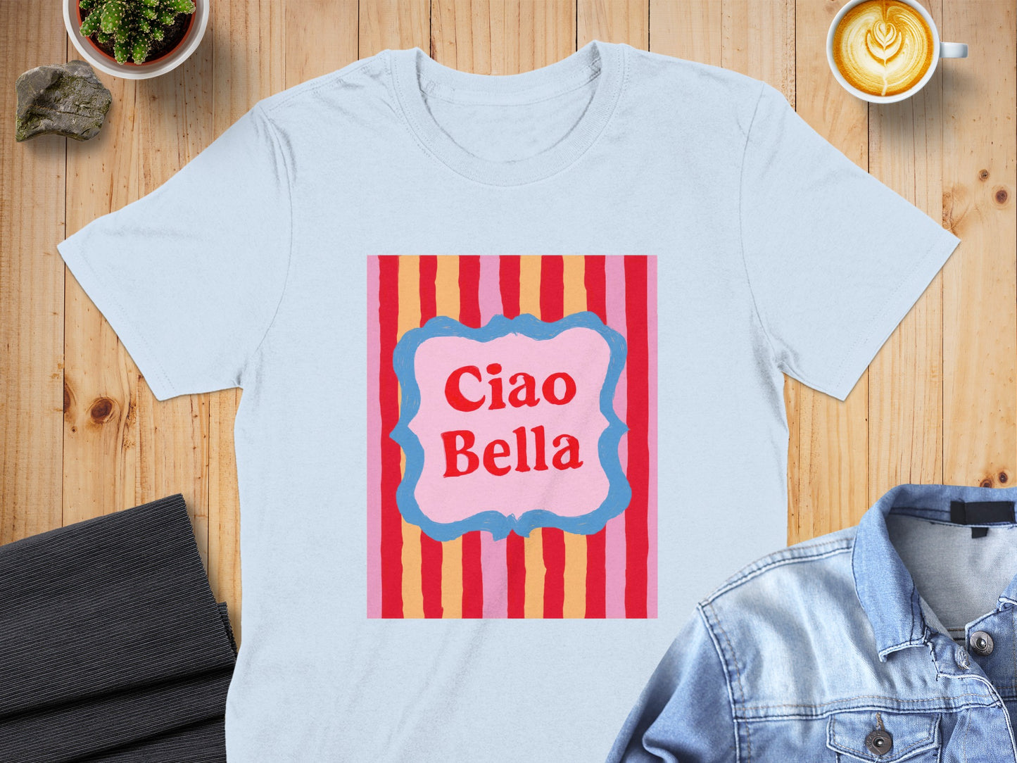 Light blue t-shirt with "Ciao Bella" text in a pink frame against a striped background.