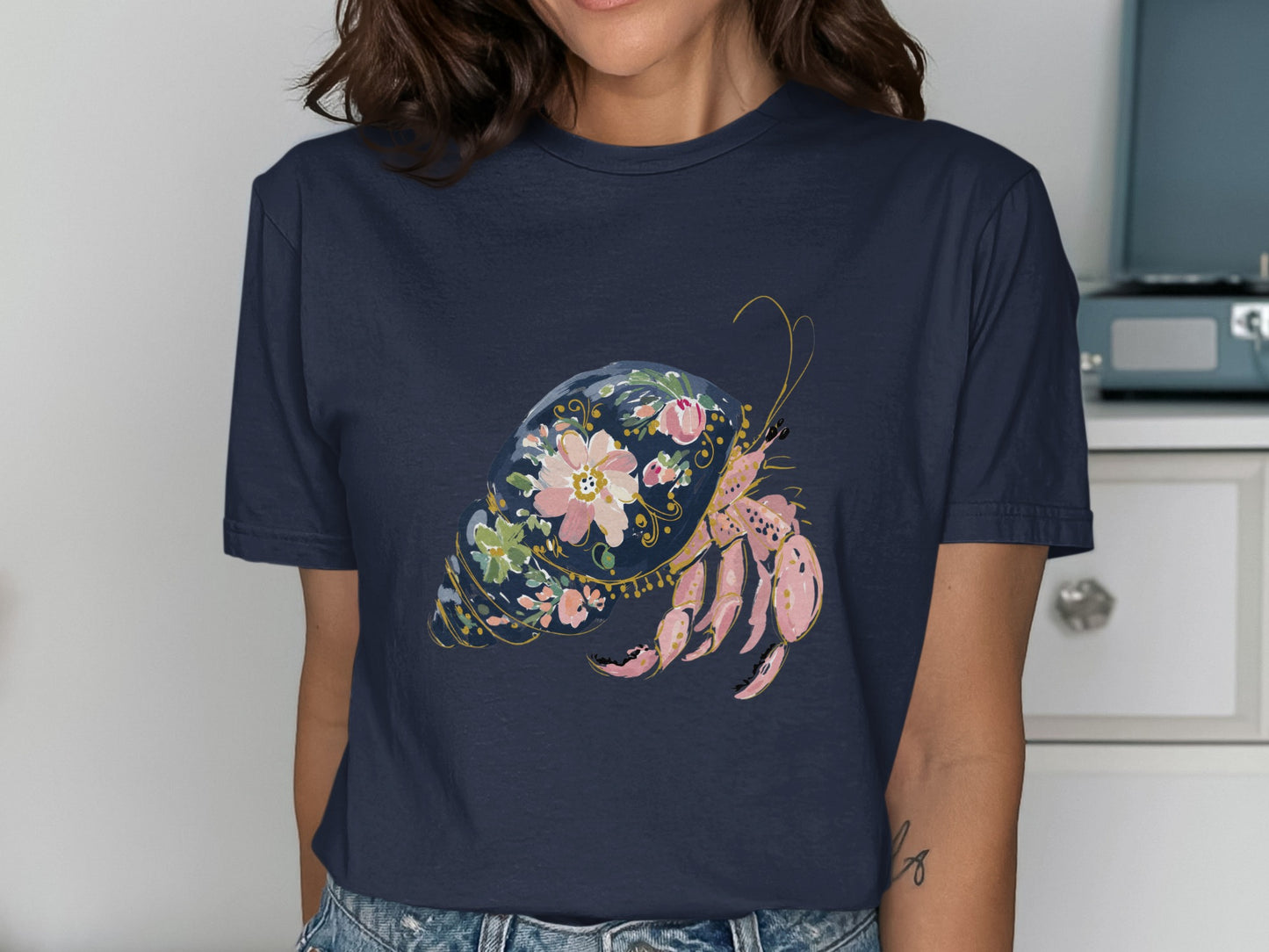 Navy t-shirt featuring a pink hermit crab in a floral shell design.