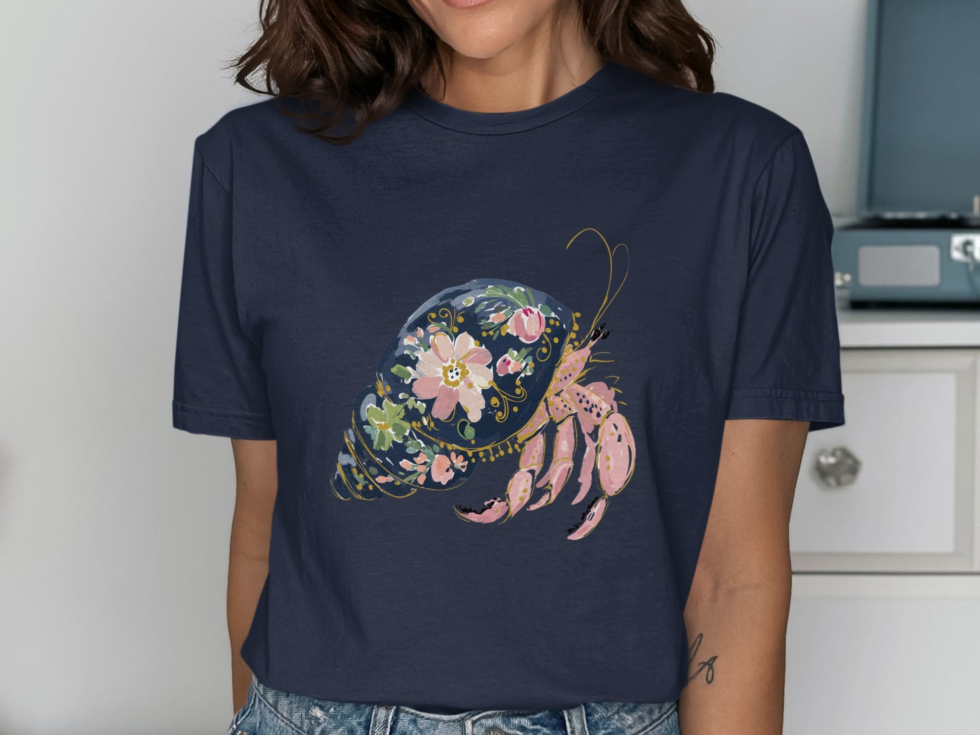 Navy t-shirt featuring a pink hermit crab in a floral shell design.