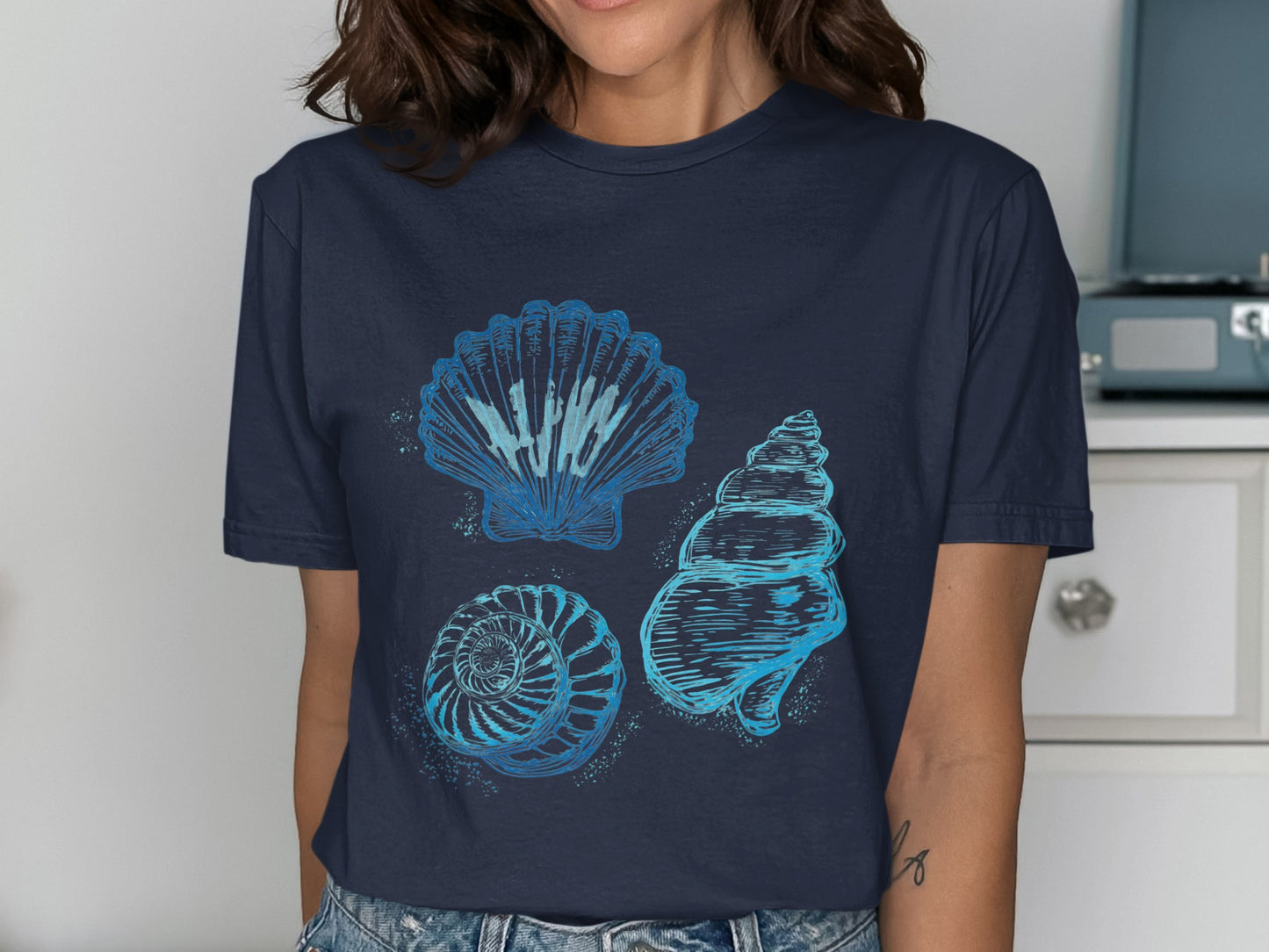Three blue line art seashells and spiral shell on a dark t-shirt.