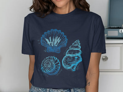 Three blue line art seashells and spiral shell on a dark t-shirt.